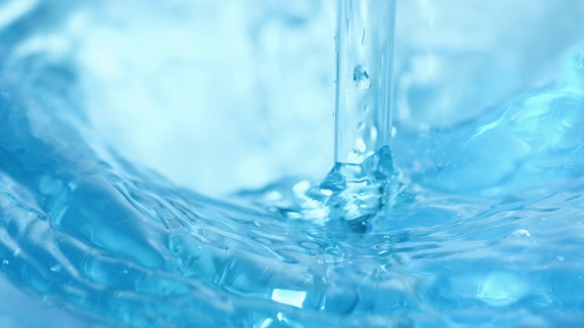 用玻璃棒搅拌蓝色的水，做出波浪和siwrls，在近距离和缓慢的动作视频购买