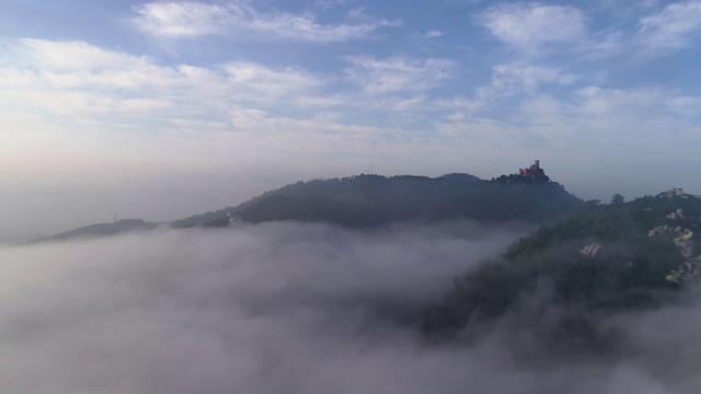 鸟瞰云雾之下的山峦和山峰上的宫殿视频下载