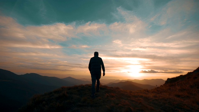 一个人站在山上，映衬着美丽的夕阳视频下载