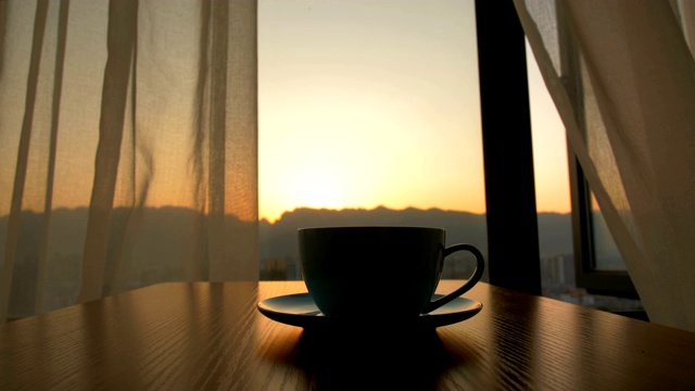 在日出的背景下，咖啡杯放在桌上视频下载