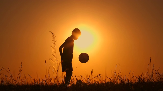 小男孩足球运动员剪影，练习用球，日落黄金时，慢动作。视频购买