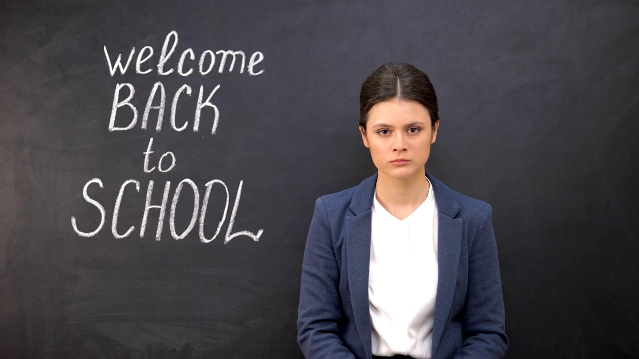 紧张的老师看着站在黑板旁边的摄像机，欢迎回到学校视频下载