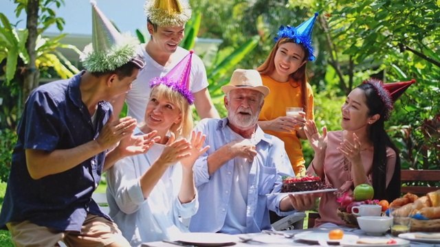 多元化家庭在户外花园家中享受老人生日派对视频下载