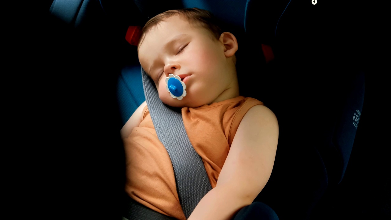 一个小男孩睡在椅子上。汽车中的儿童安全系统。视频购买