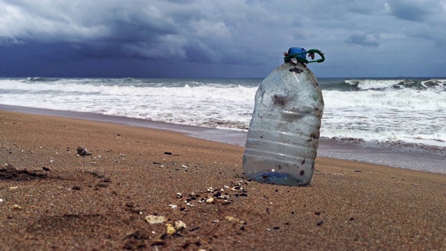 一个一次性塑料瓶污染了一个暴风雨的海滩视频素材