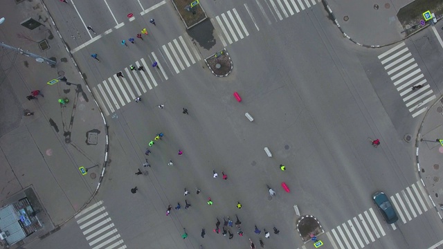 空中从上往下拍摄的城市道路十字路口与人们跑马拉松视频下载