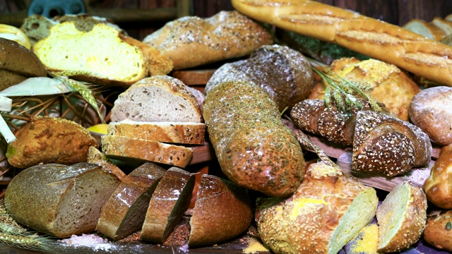 餐桌上有大量可供选择的新鲜面包。前景拍摄的是玉米面包、南瓜籽面包和编面包。视频素材