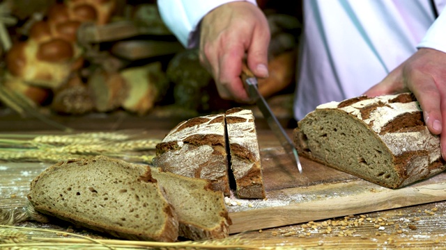 面包店的面包师把硬皮面包切成片。视频素材