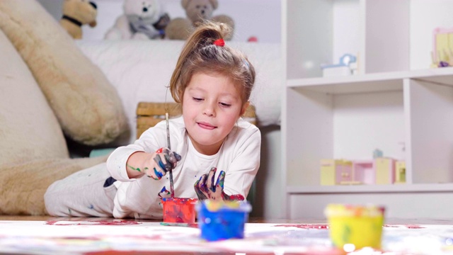 一个小女孩的肖像躺在她卧室的地板上，颜色和彩色水粉。视频素材