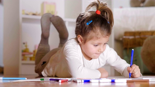 两个小女孩的肖像躺在他们卧室的地板上，用彩色毡尖笔进行艺术绘画。视频素材