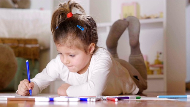 两个小女孩的肖像躺在他们卧室的地板上，用彩色毡尖笔进行艺术绘画。视频素材