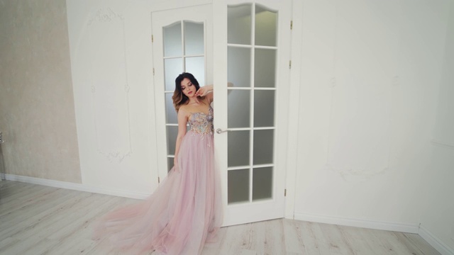 美丽的新娘穿着婚纱站在灯光房的门口。视频素材