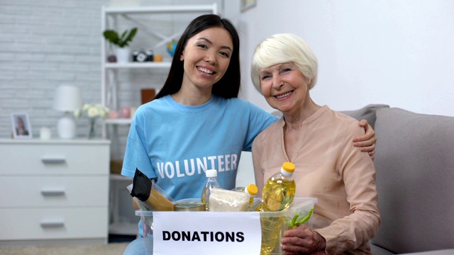 有爱心的积极分子拥抱拿着捐赠食品盒的女性养老金领取者，支持视频素材