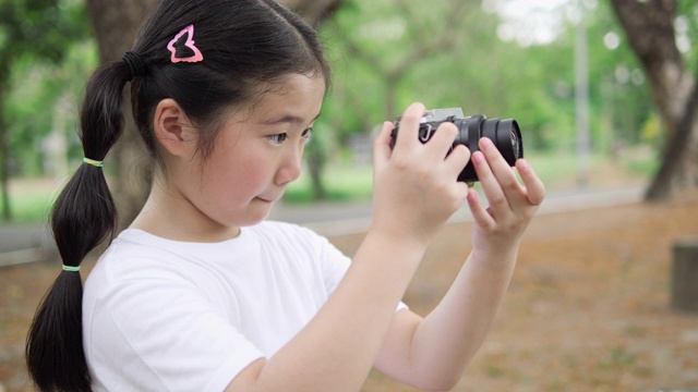 亚洲小女孩用相机拍摄大自然。技术理念，拍照体验生活。4K分辨率和慢镜头。视频下载