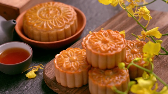 美麗的月餅在木托盤與茶和花在黑石板背景。中國傳統的中秋節觀念。視頻素材