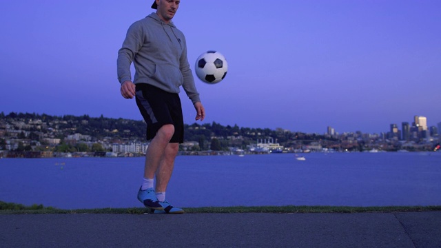 紫色城市湖日落与年轻人耍足球视频下载