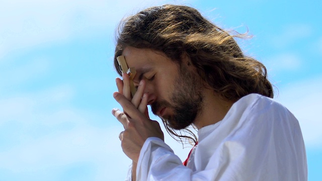 圣人闭着眼睛亲吻十字架，向上帝祈祷灵魂的拯救视频素材