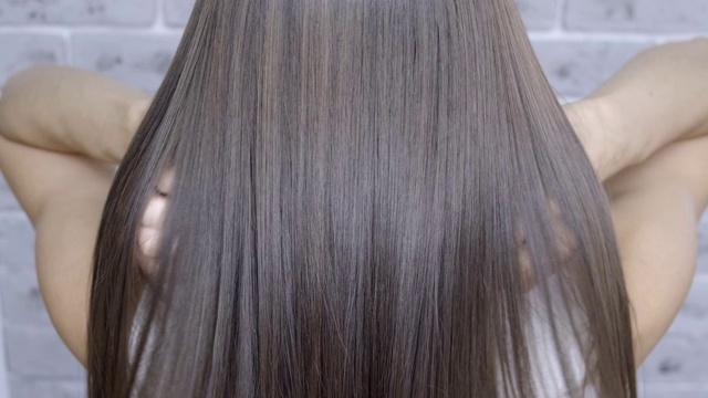 一个棕色头发的女孩在美容院做头发分层和拉直后的结果。头发护理的概念视频下载