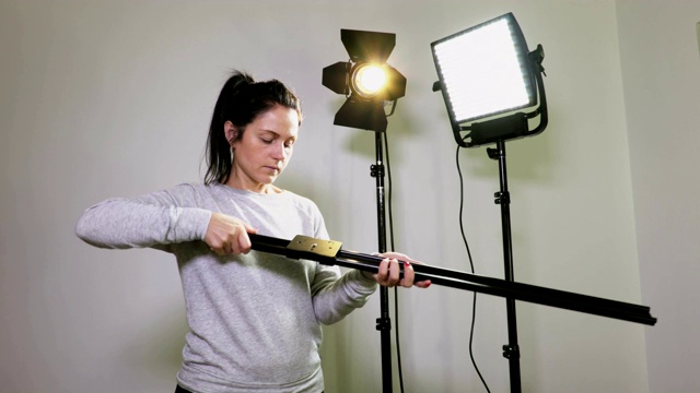 女摄影师检查相机滑块附近的LED菲涅耳和LED面板灯视频下载