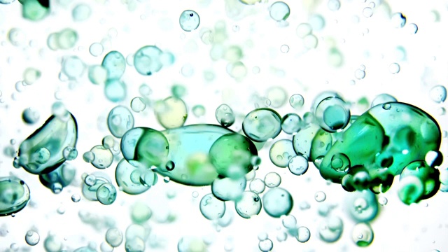 近距离和缓慢的运动倒蓝色和绿色的液体从右边和创造一排泡沫，而弹跳周围的水视频素材