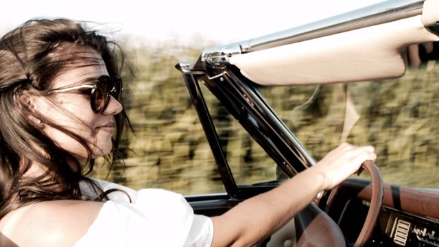 肖像无忧无虑的年轻女子驾驶敞篷车沿着阳光明媚的乡村田野视频购买