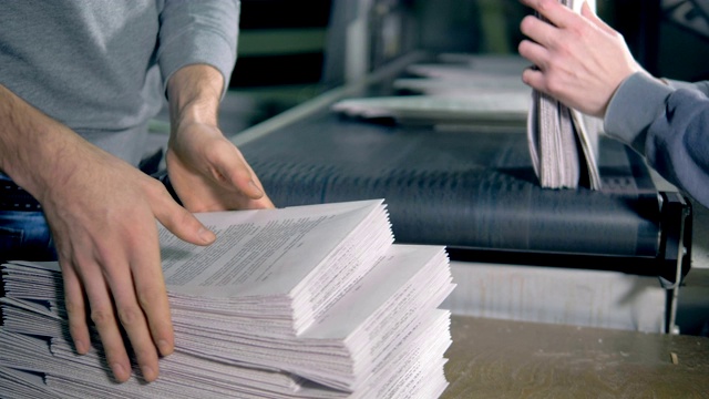 男人们在纸上工作，把纸叠起来，近距离堆放。视频素材