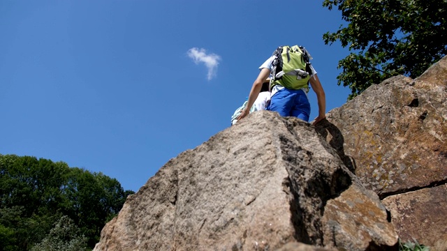 徒步旅行的男人帮助女人爬上陡峭的岩石视频下载