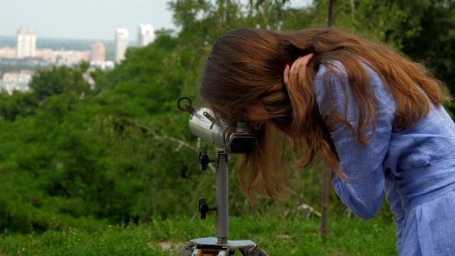 一个穿蓝色衣服的女人在用望远镜看视频下载