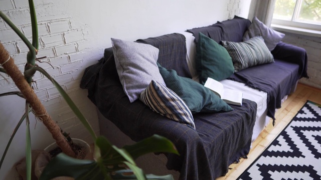 一个大的自制花旁边是一个漂亮舒适的沙发，有枕头和格子呢。Hygge konpet。视频素材