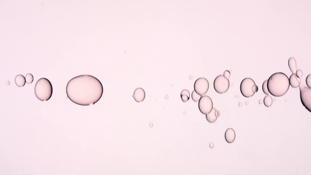近距离慢镜头，一排粉红色的油泡在浅粉色的背景上跳跃视频素材