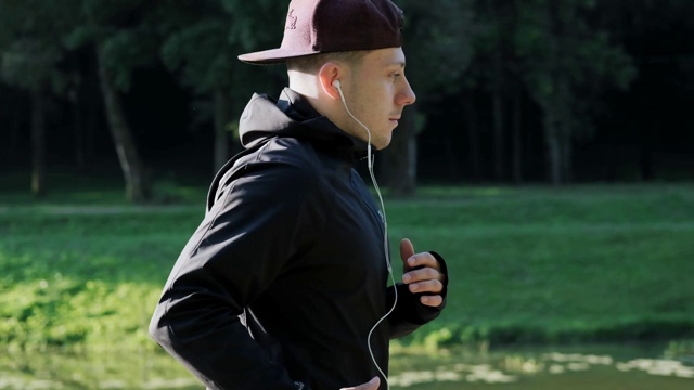 年轻人训练跑步。男性穿着黑色运动服，戴着头戴耳机。视频素材