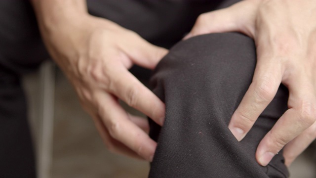 亚洲男人按摩他的膝盖疼痛和感觉不好。触发点医疗保健概念视频素材