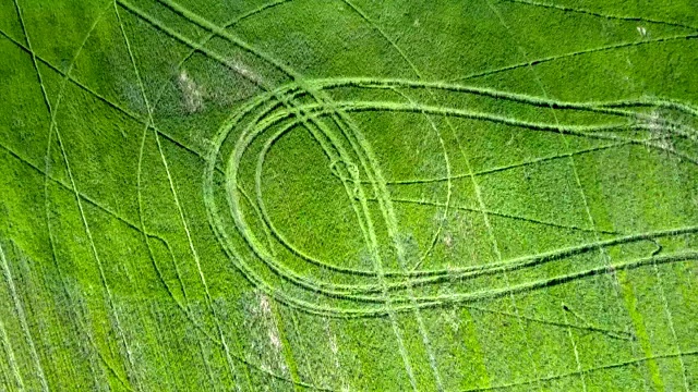 上视图拖拉机痕迹在绿色的田野视频下载