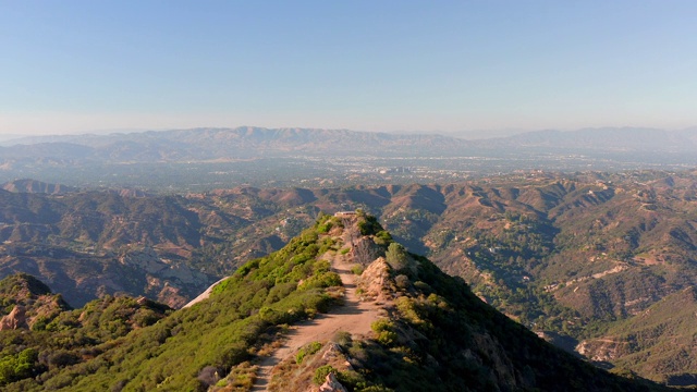 航拍:在阳光明媚的日子里，无人机移动在一名坐在悬崖峭壁上的妇女身上，这是加利福尼亚州洛杉矶视频下载