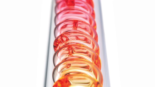 近距离观察黄色、橙色和红色的液体在科学玻璃冷凝器中螺旋下降的慢动作视频素材