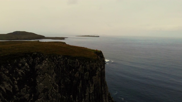 穿着荧光雨衣的家伙在苏格兰斯凯岛海岸线的悬崖上。视频下载