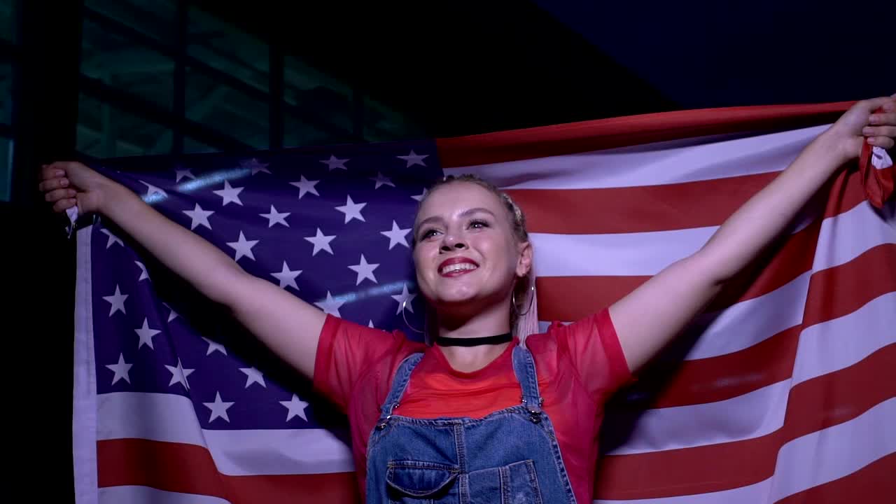 年轻时尚的女人挥舞着美国国旗，在音乐会上消遣，慢动作视频下载