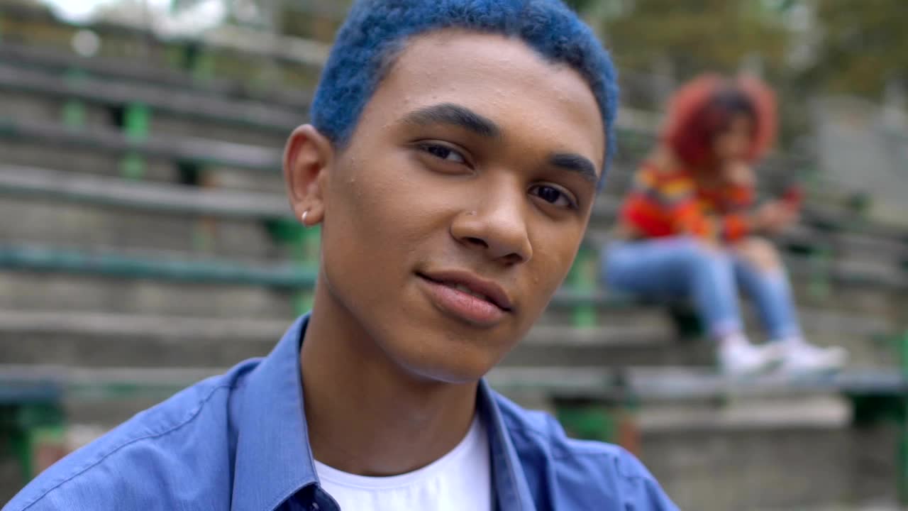 一个自信的蓝头发黑人少年在镜头前微笑，青春期视频下载