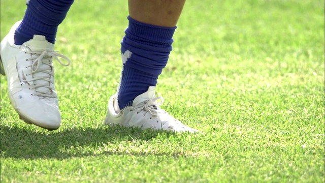穿着钉鞋的脚在草地上反复踢足球。视频下载