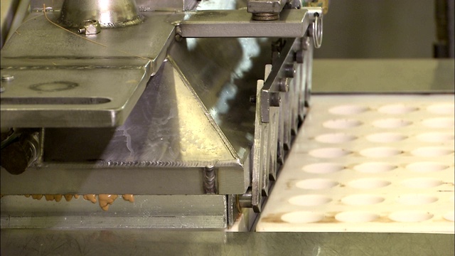 一台机器将花生酱放入糖果模具中。视频素材