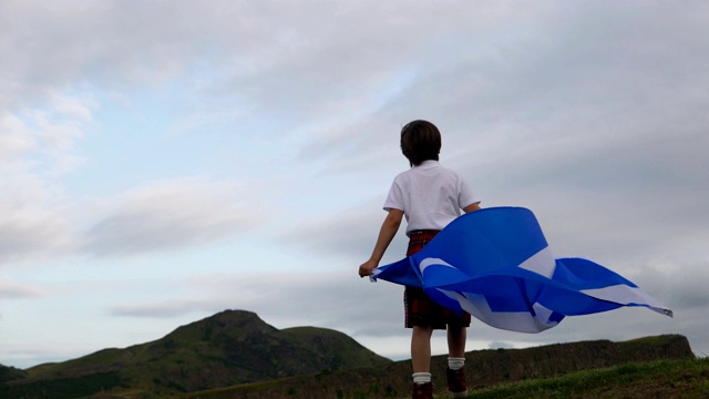 一个悲伤的男孩拿着苏格兰国旗，背景是亚瑟的座位山视频下载