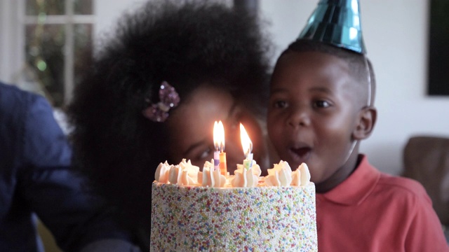 年轻的非洲裔美国孩子在生日派对上吹蜡烛，特写视频下载