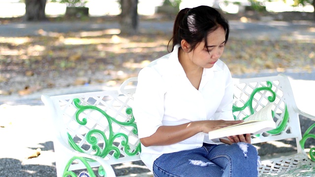 一位妇女正在公园里看书。视频素材