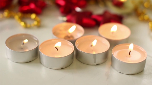 白色的蜡烛放在白色的桌子上，点缀着红色和金色的圣诞装饰品视频下载