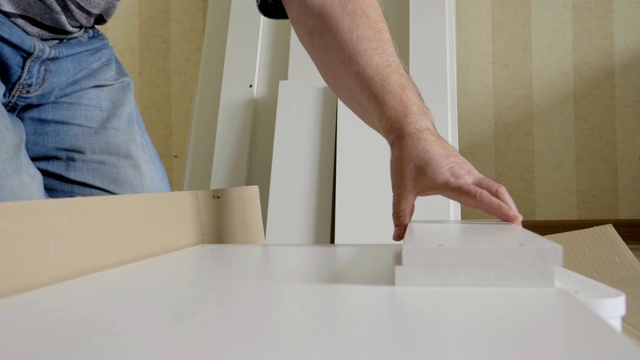 工人在组装前打开盒子取出白色木制家具的部件视频下载