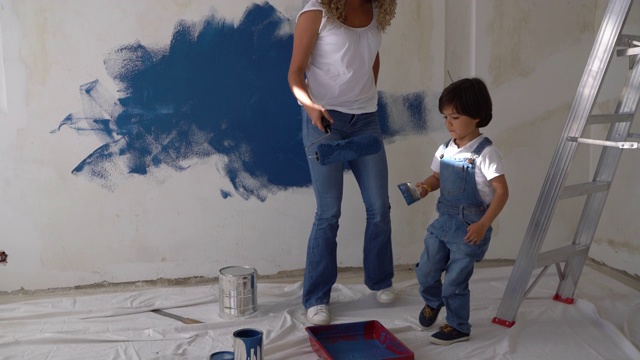 可爱的妈妈和儿子在做一个DIY的项目，在家里刷墙视频素材