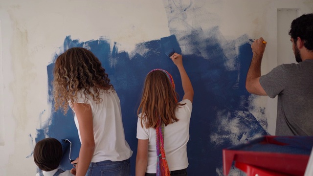 后视图拉丁美洲年轻的家庭油漆墙壁与蓝色在家里视频素材