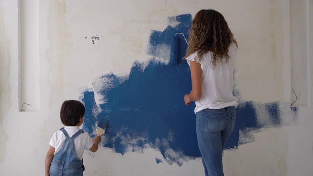 快乐的妈妈和儿子有乐趣在家里刷墙视频素材
