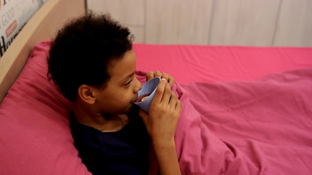 年轻的女孩病在床上与温度喝热茶视频素材