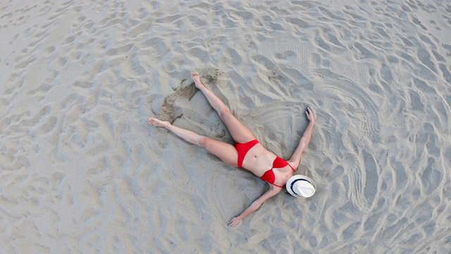 百慕大日光浴，美丽的黑发女孩躺在空旷的海滩上晒太阳，从上面鸟瞰视频下载